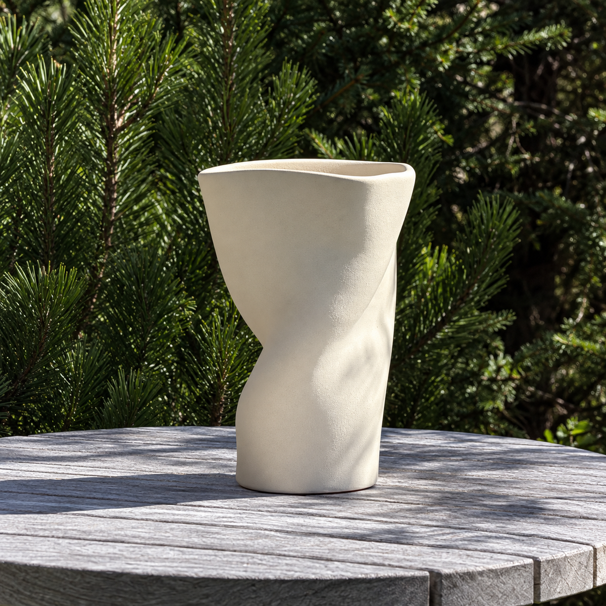 SŌL Vase auf einem runden Holztisch vor grünen Bäumen